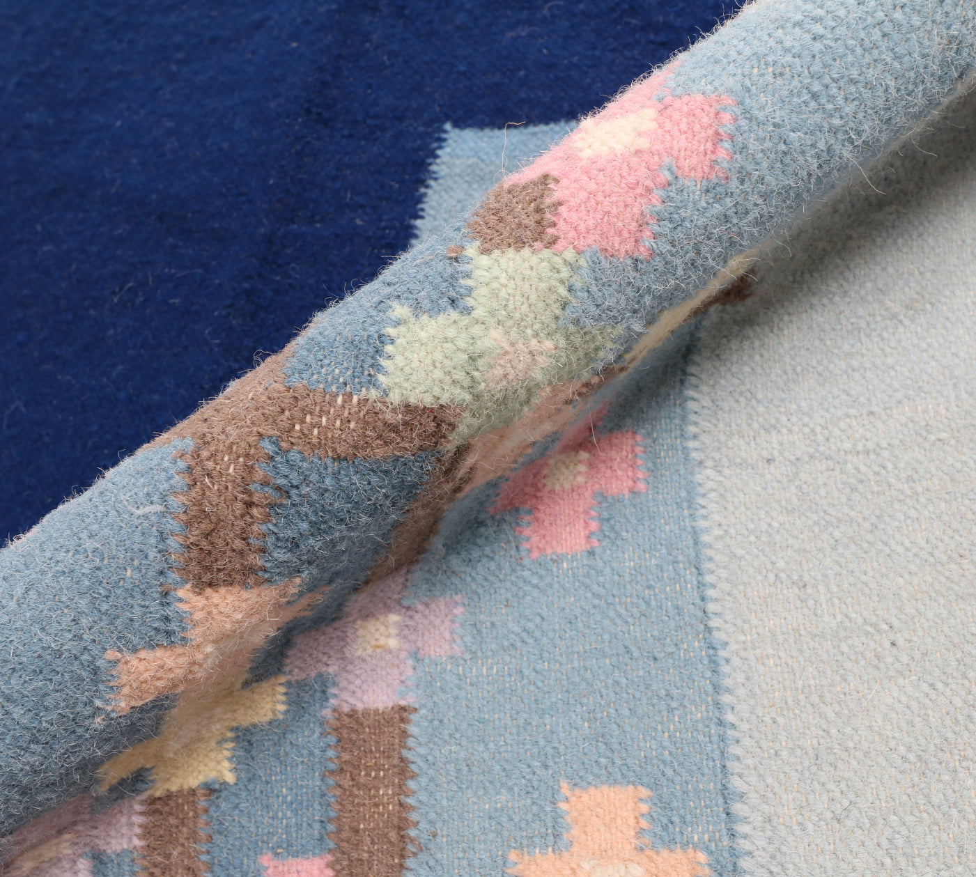 Close-up of a textured rug with geometric pattern on a blue background