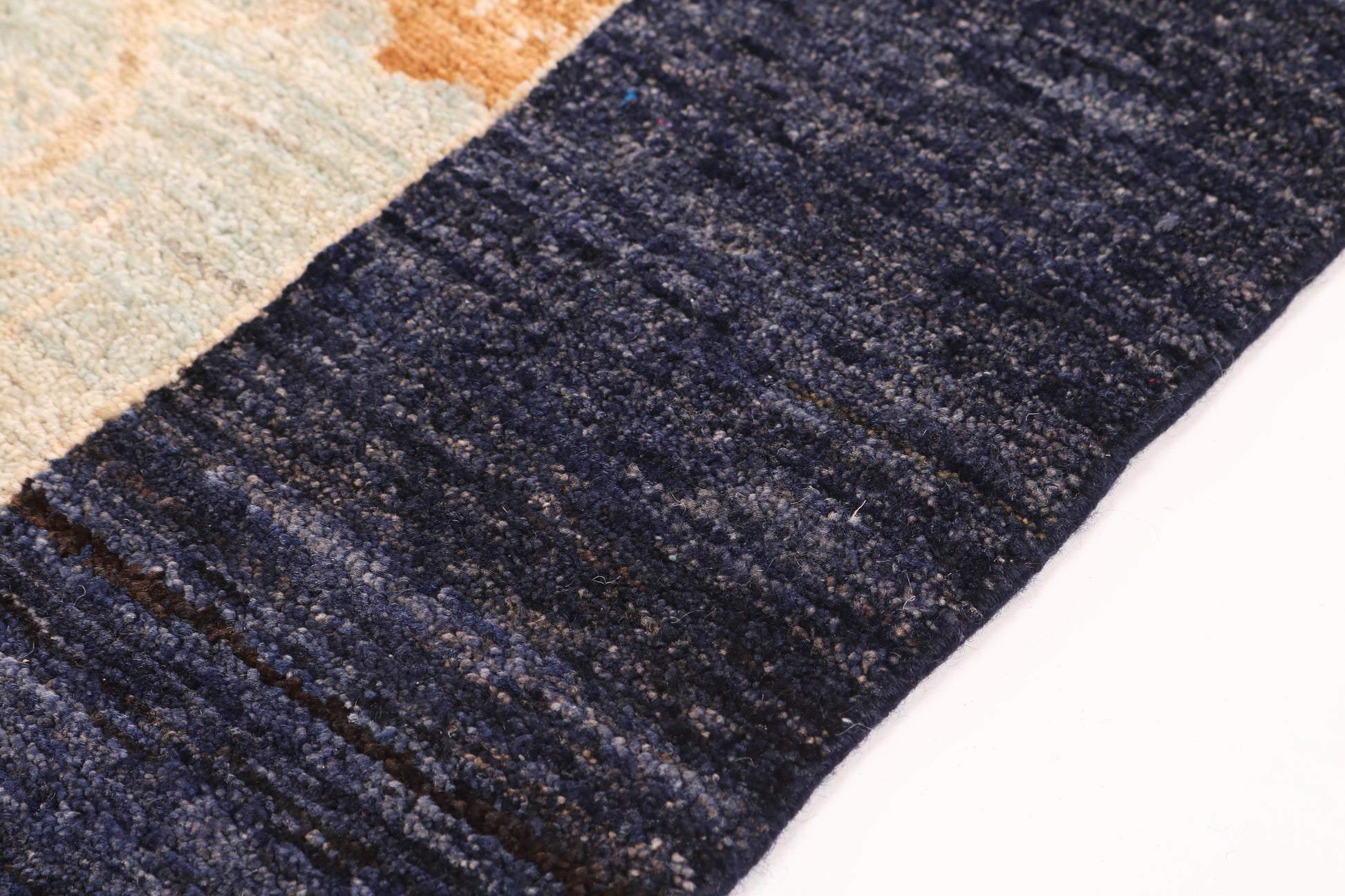 Close-up of a textured blue rug with a neutral-colored pattern in the background