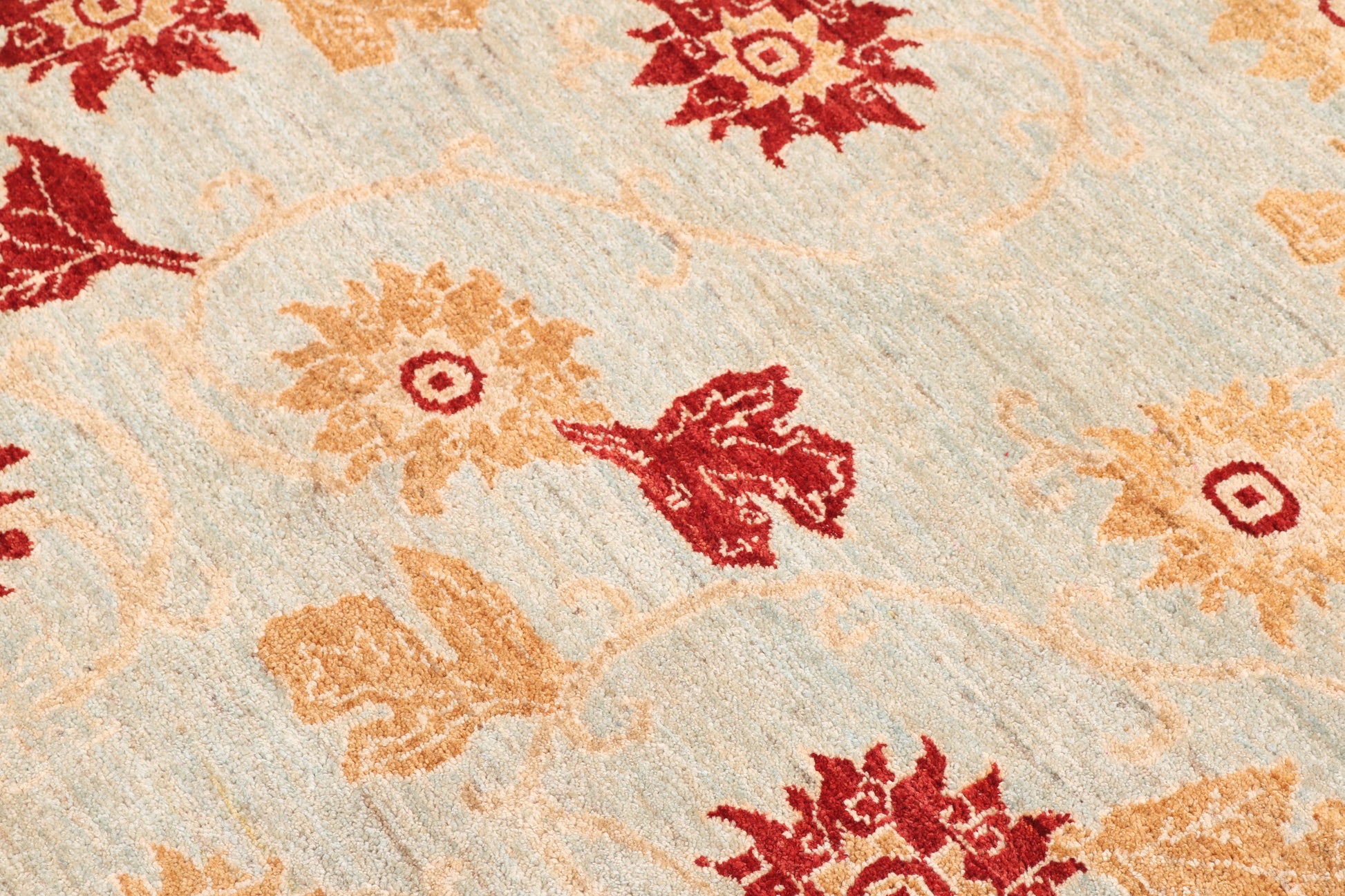 Close-up of a floral patterned rug with red and orange flowers on a beige background
