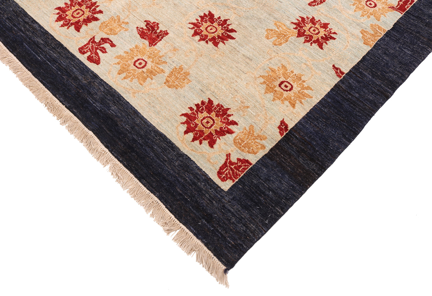 Corner of a patterned rug with red and orange floral designs on a beige background.