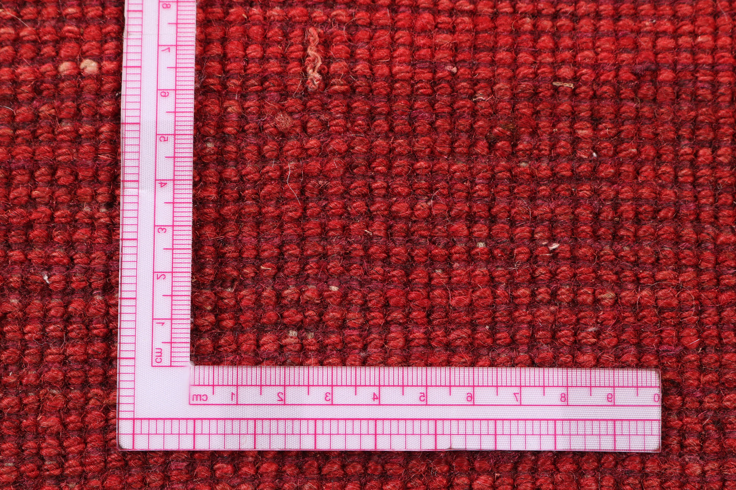 Red textured rug with a clear ruler for scale