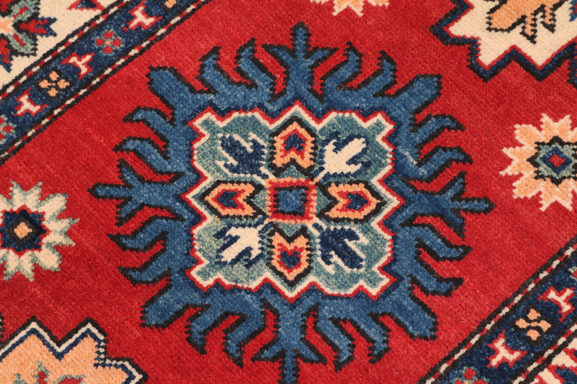 Close-up of a red rug with intricate blue and beige patterns