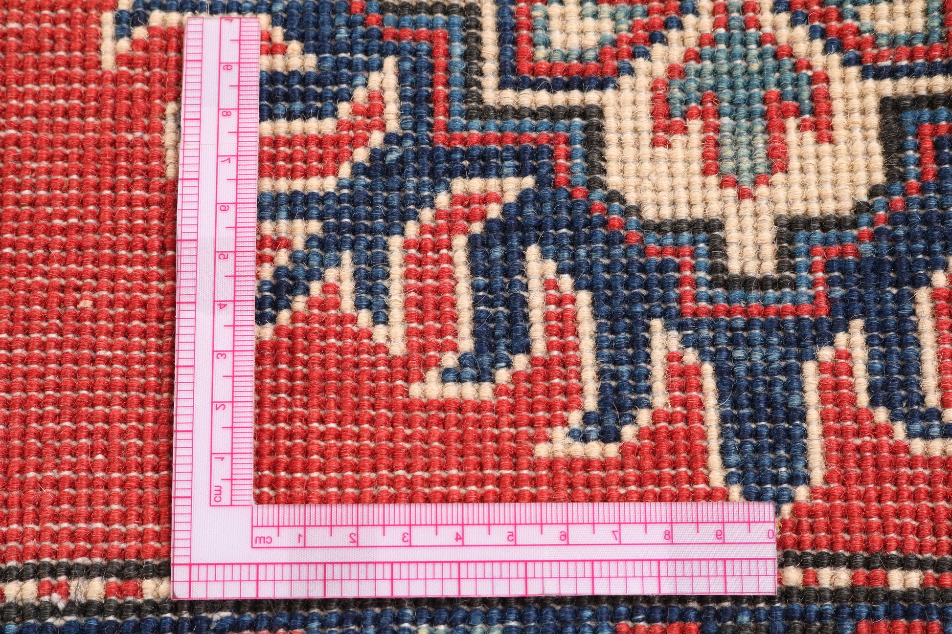 Rug with intricate patterns and a pink measuring ruler on top