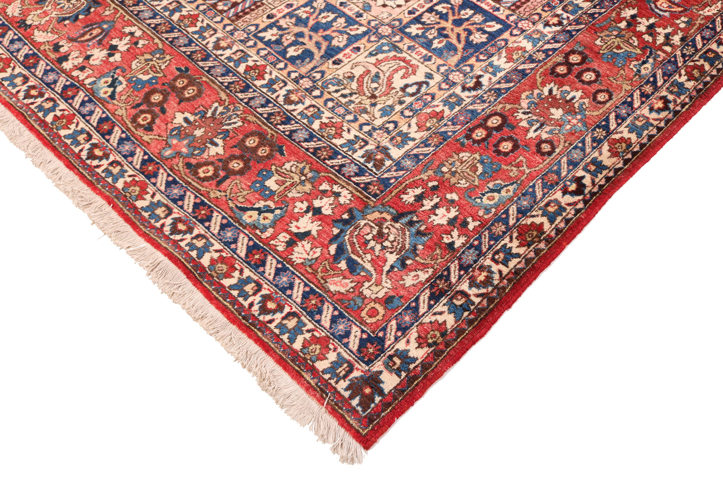 Corner of a patterned rug with red, blue, and beige colors on a white background