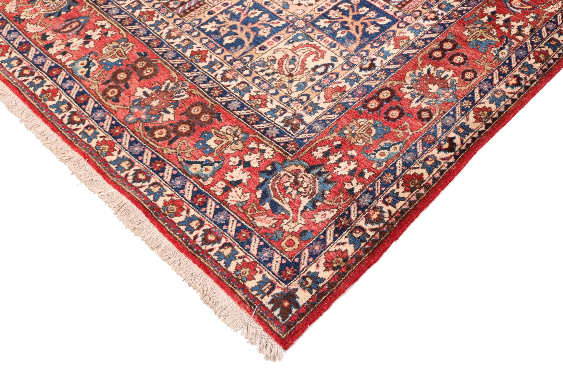 Corner of a patterned rug with red, blue, and beige colors on a white background