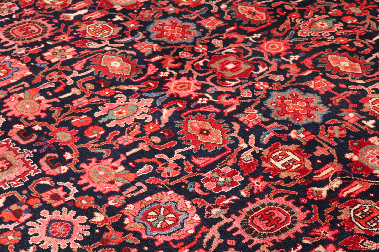 Close-up of a patterned rug with red and pink designs on a dark background