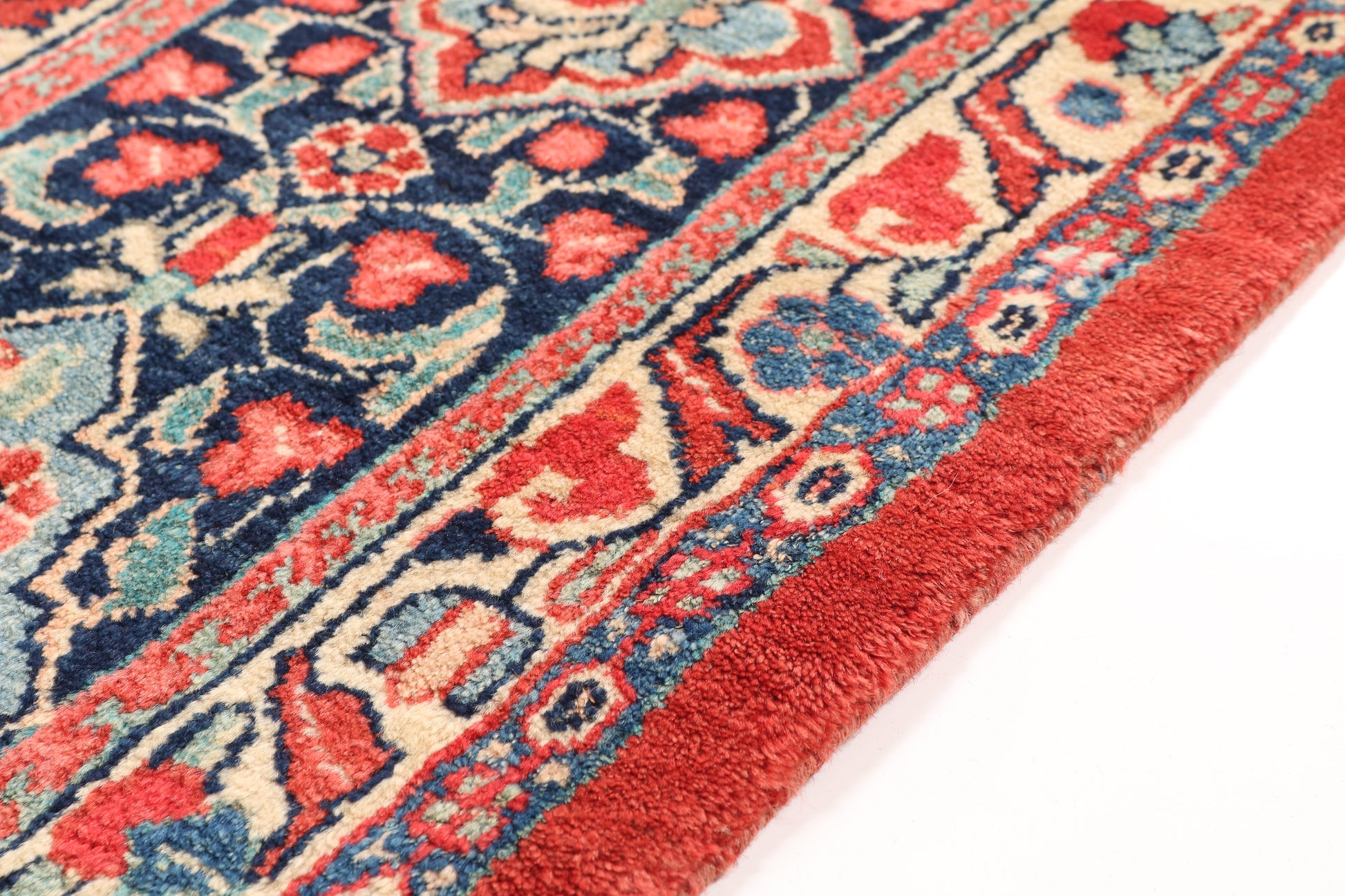 Close-up of a patterned rug with red, blue, and pink colors on a white background