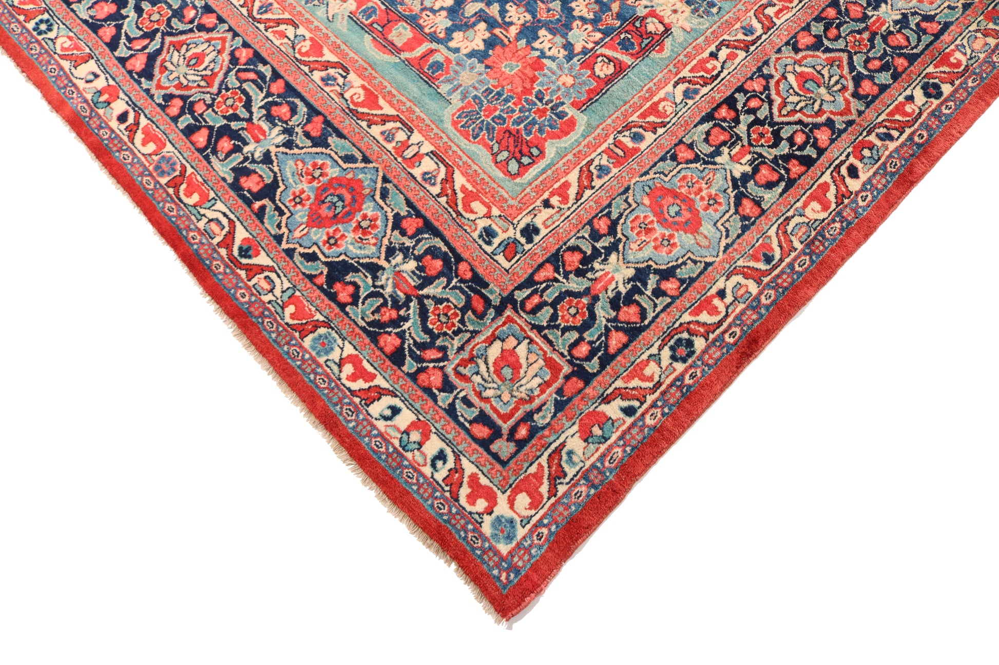 Corner of a colorful patterned rug with red, blue, and beige tones on a white background