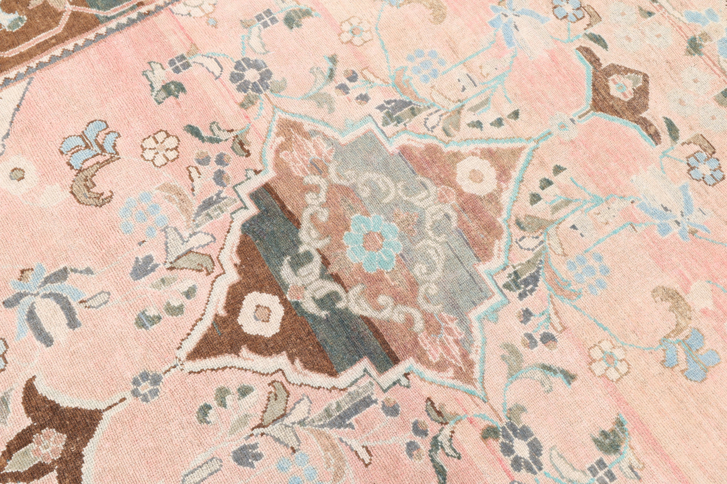 Close-up of a patterned fabric with floral and geometric designs on a pink background