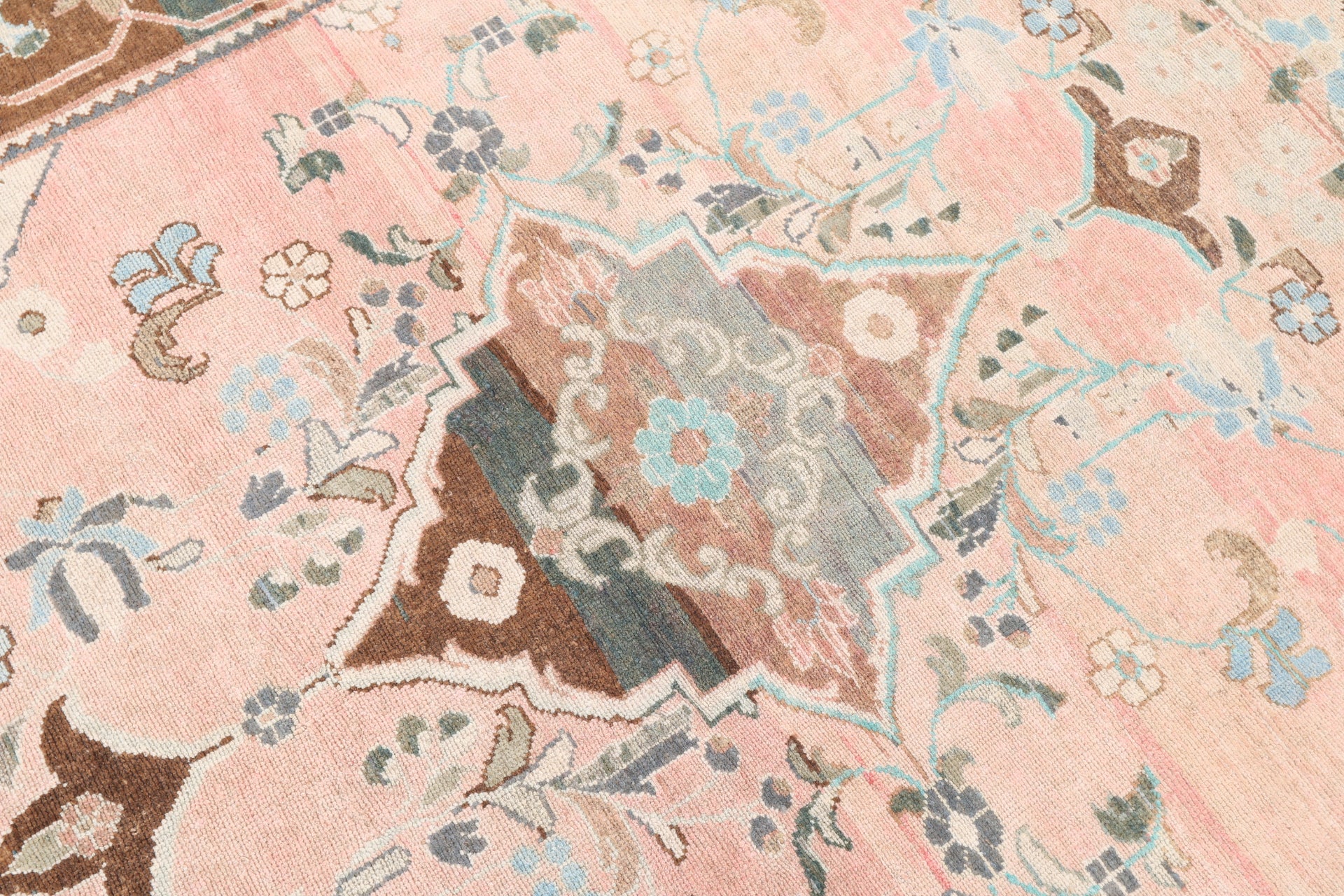 Close-up of a patterned fabric with floral and geometric designs on a pink background