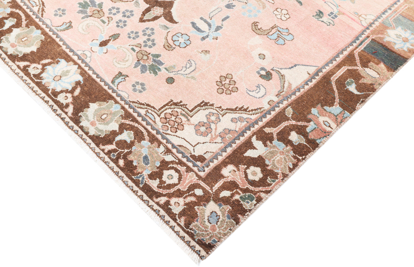 Low-profile texture shot of a hand-knotted traditional beige and pink rug, showcasing the authentic wool pile for premium event hire.