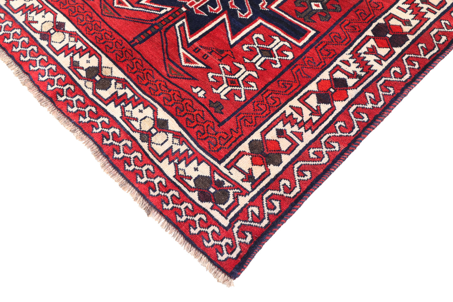 Close-up of a red and beige patterned rug corner on a white background