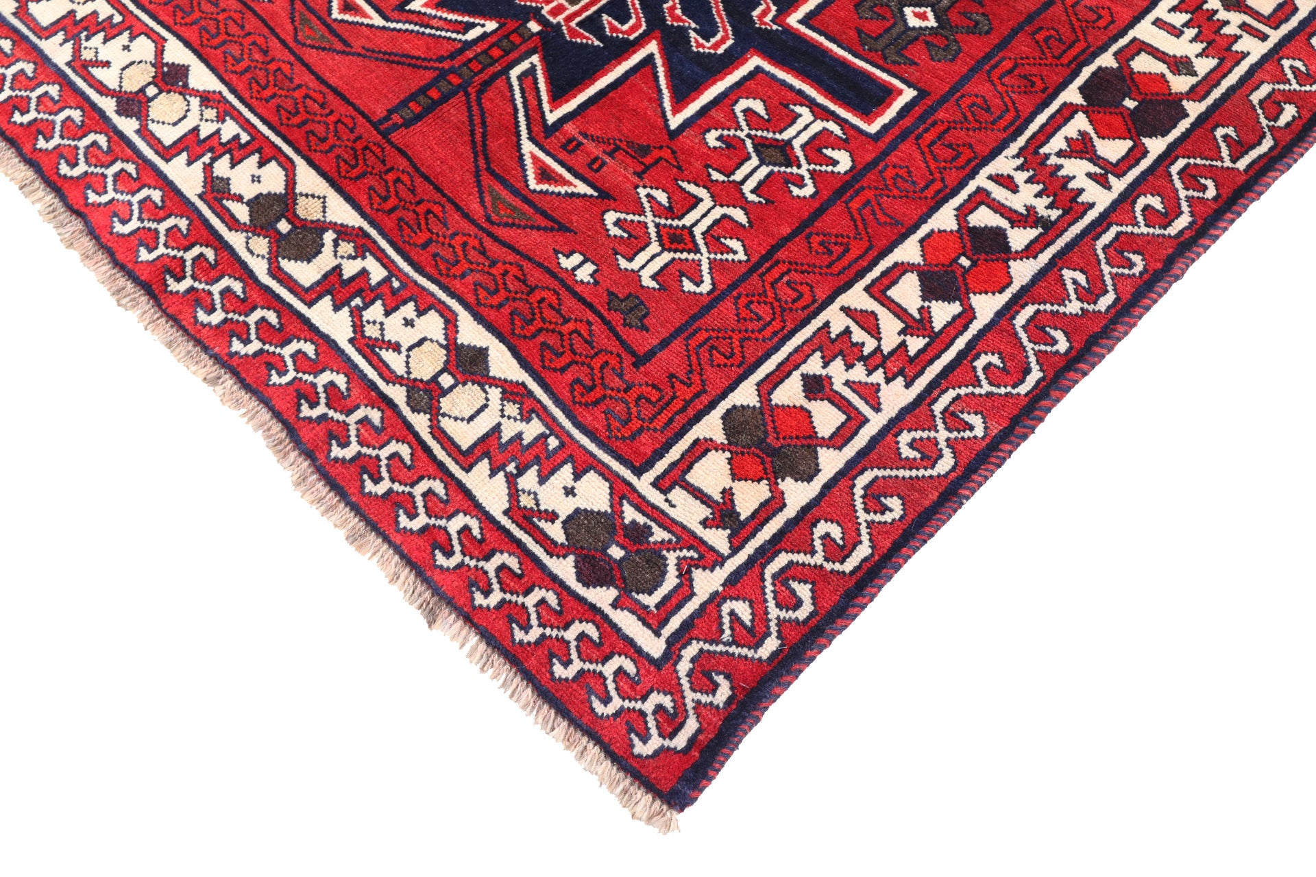 Close-up of a red and beige patterned rug corner on a white background