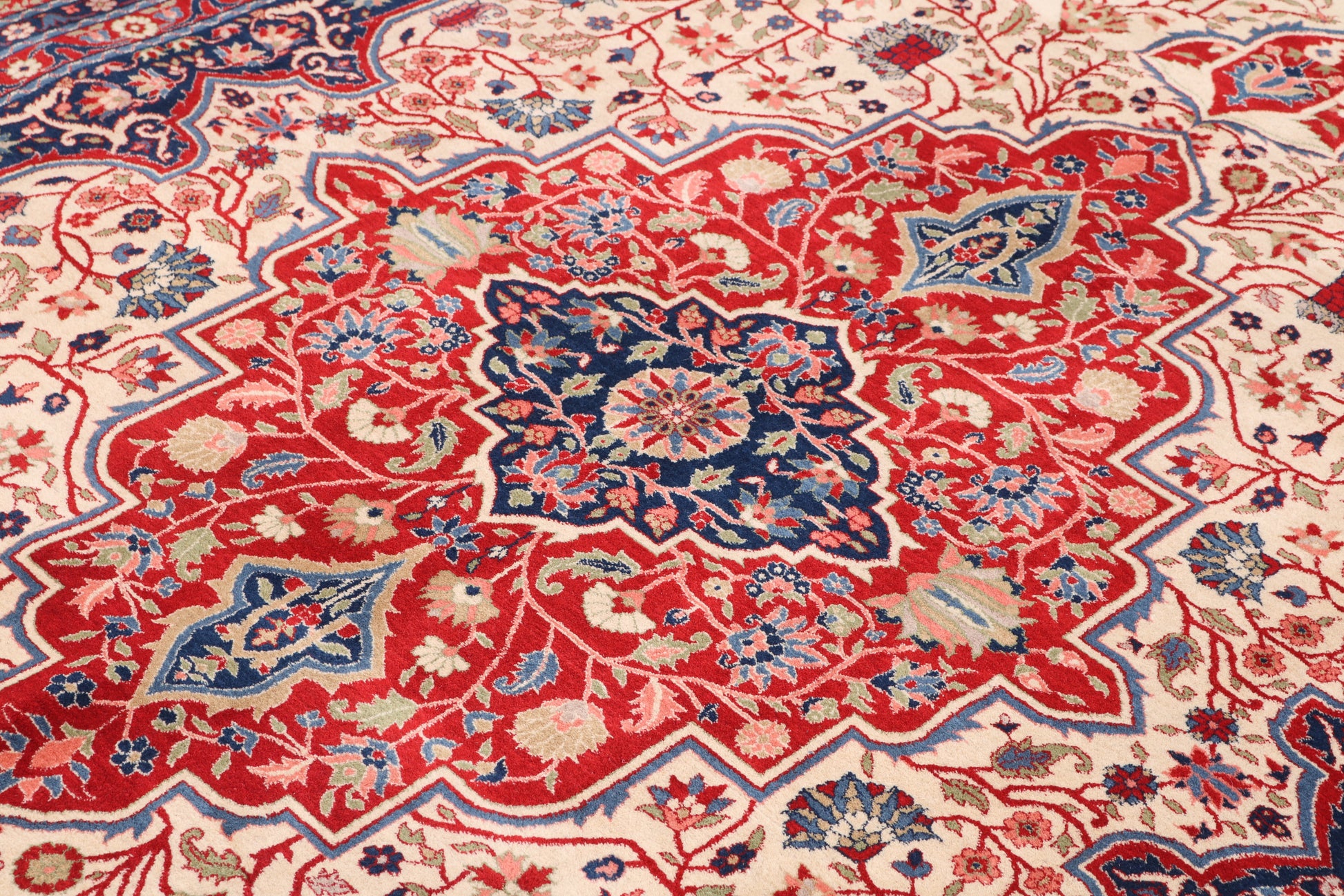 Close-up of a intricately designed red, blue, and beige rug with floral patterns.