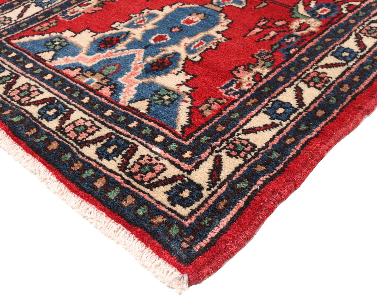 Close-up of a colorful patterned rug corner with red, blue, and beige colors.