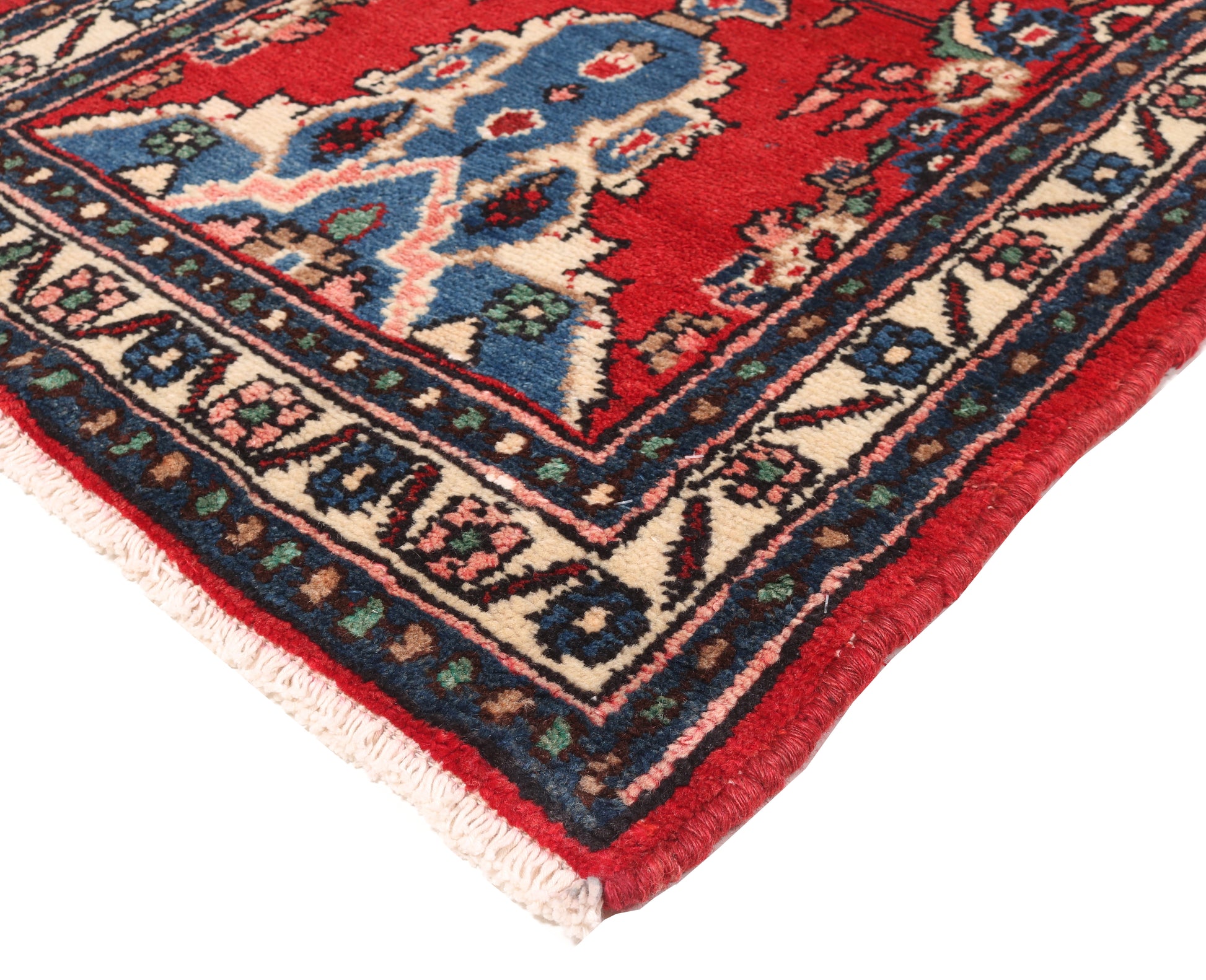 Close-up of a colorful patterned rug corner with red, blue, and beige colors.