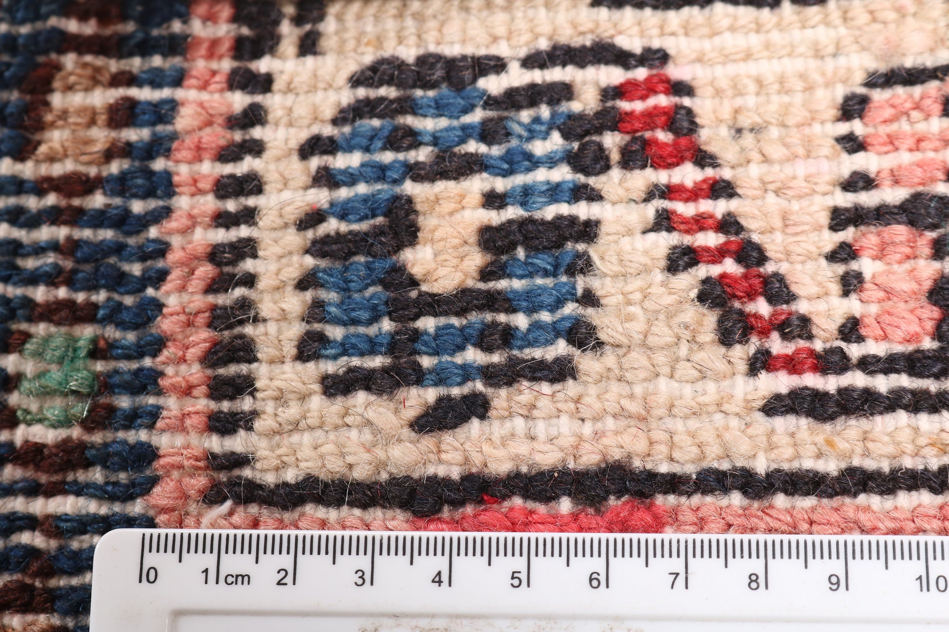 Close-up of a patterned rug with a ruler for scale