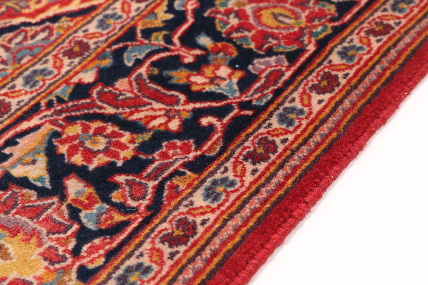 Detailed corner shot of a traditional red rug highlighting the intricate navy blue floral border and authentic hand-knotted weave.