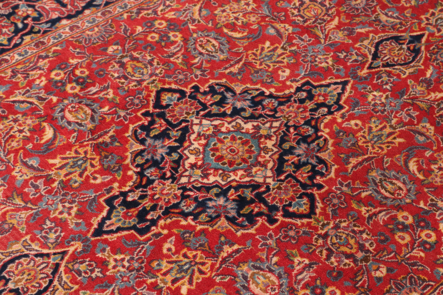 The central floral medallion in mixed ruby, blue, and cream tones, ideal for high-definition film set close-ups.