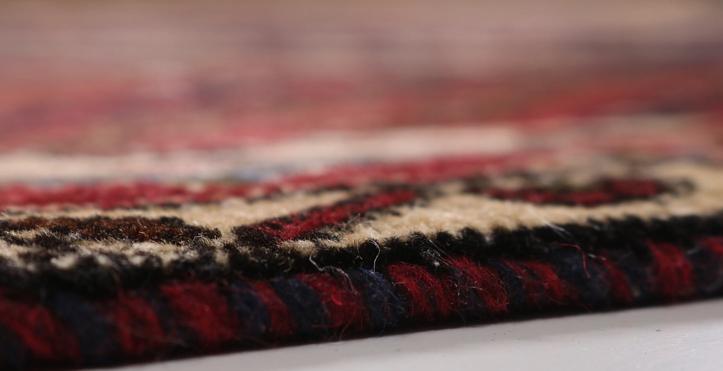Close-up of a textured rug with red, black, and beige patterns on a blurred background