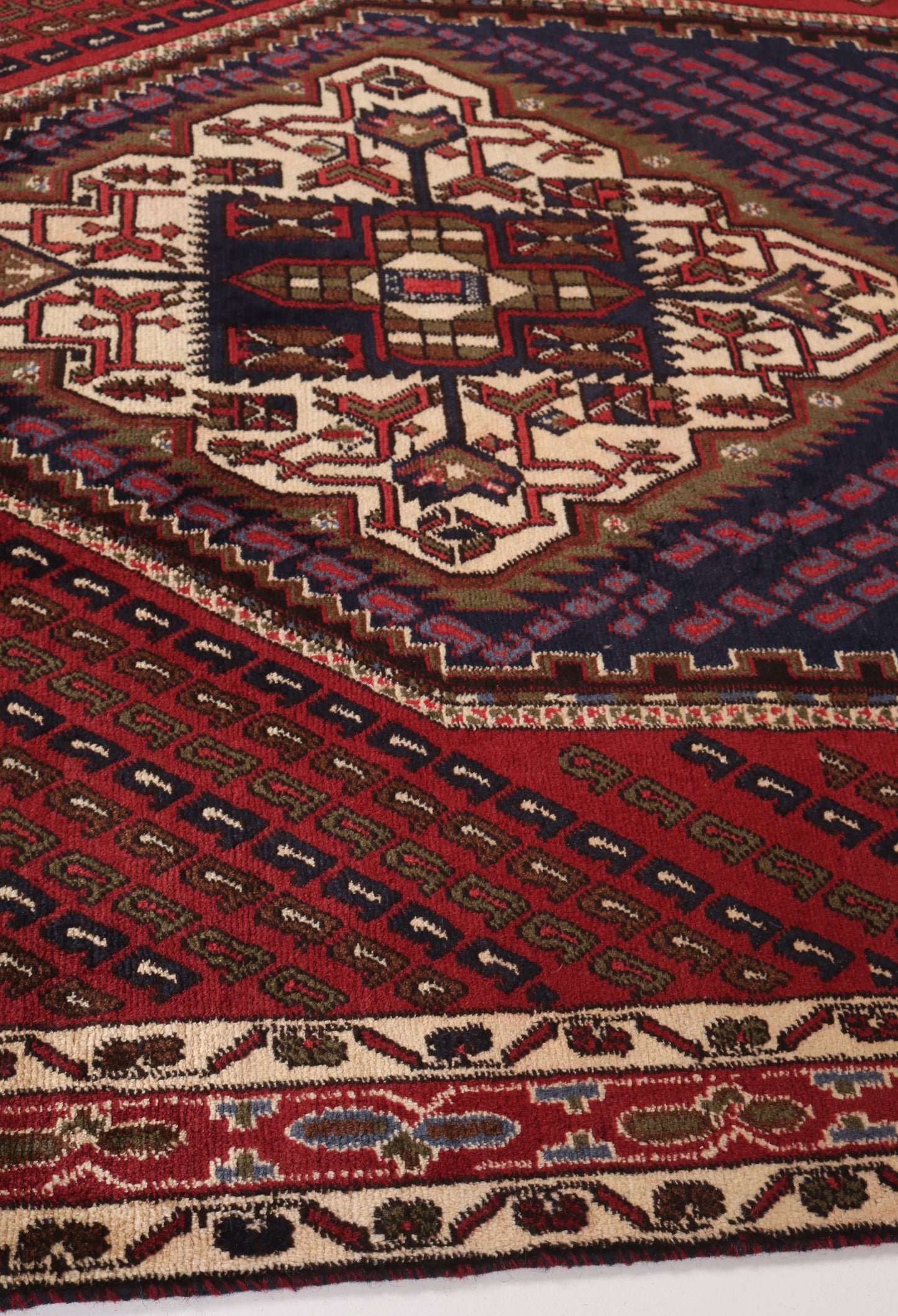 Close-up of a patterned rug with intricate designs on a red and brown background.