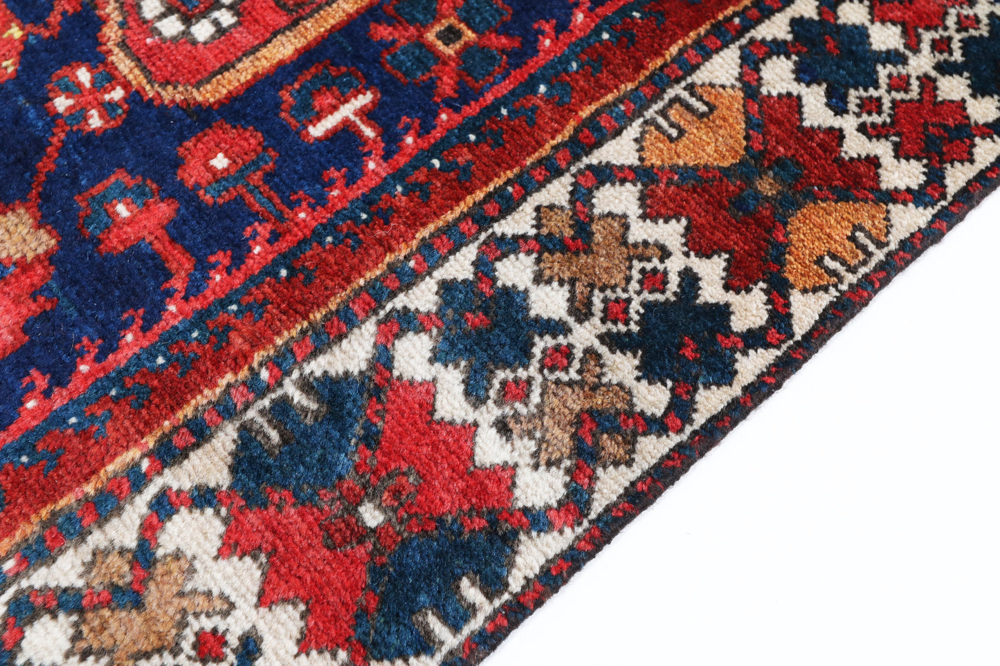 Close-up of a patterned rug with red, blue, and beige colors.