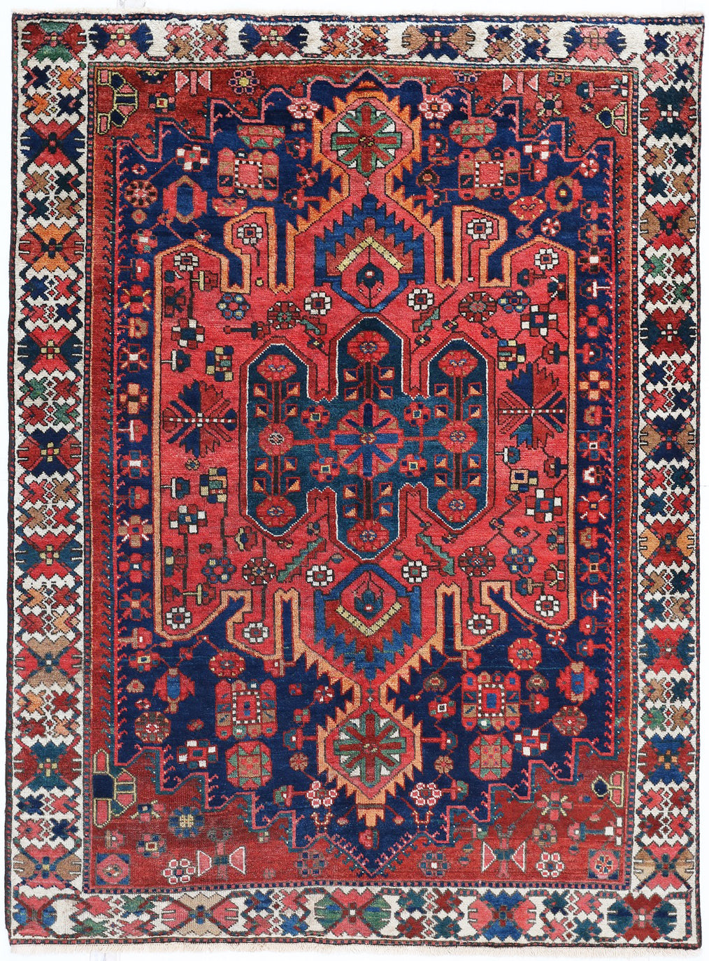 Decorative rug with intricate patterns in red, blue, and beige on a white background