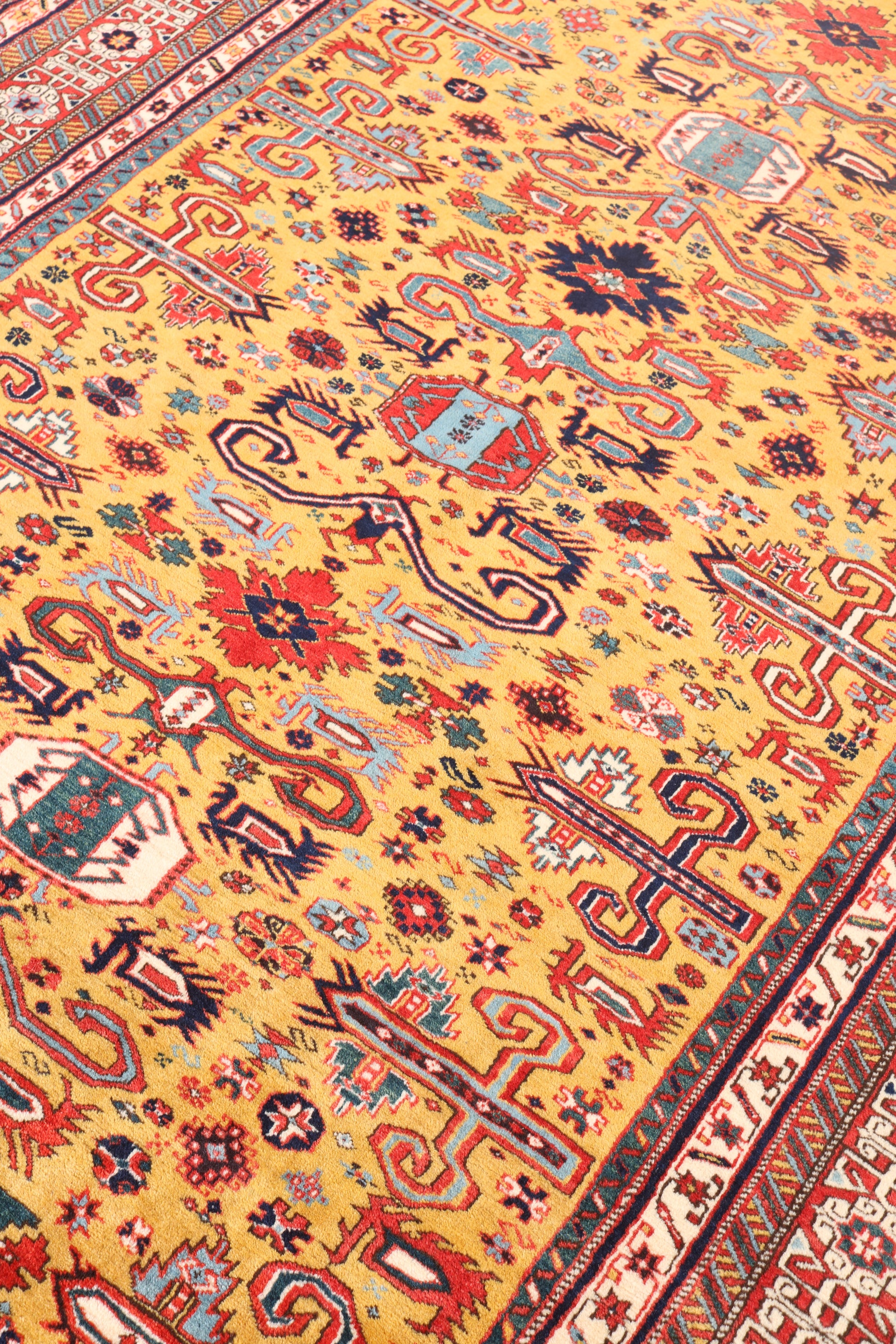 Close-up of a colorful patterned rug with intricate designs on a yellow background.